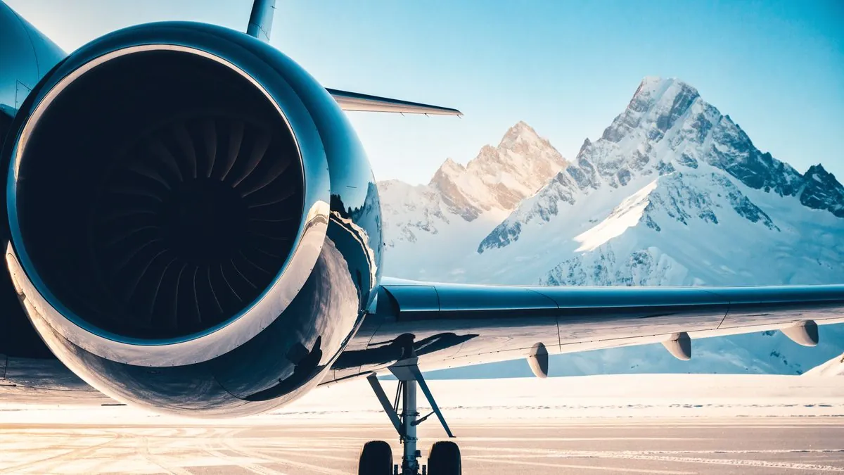 Private jet engine and landing gear on a snowy apron, jagged snow-covered peaks behind
